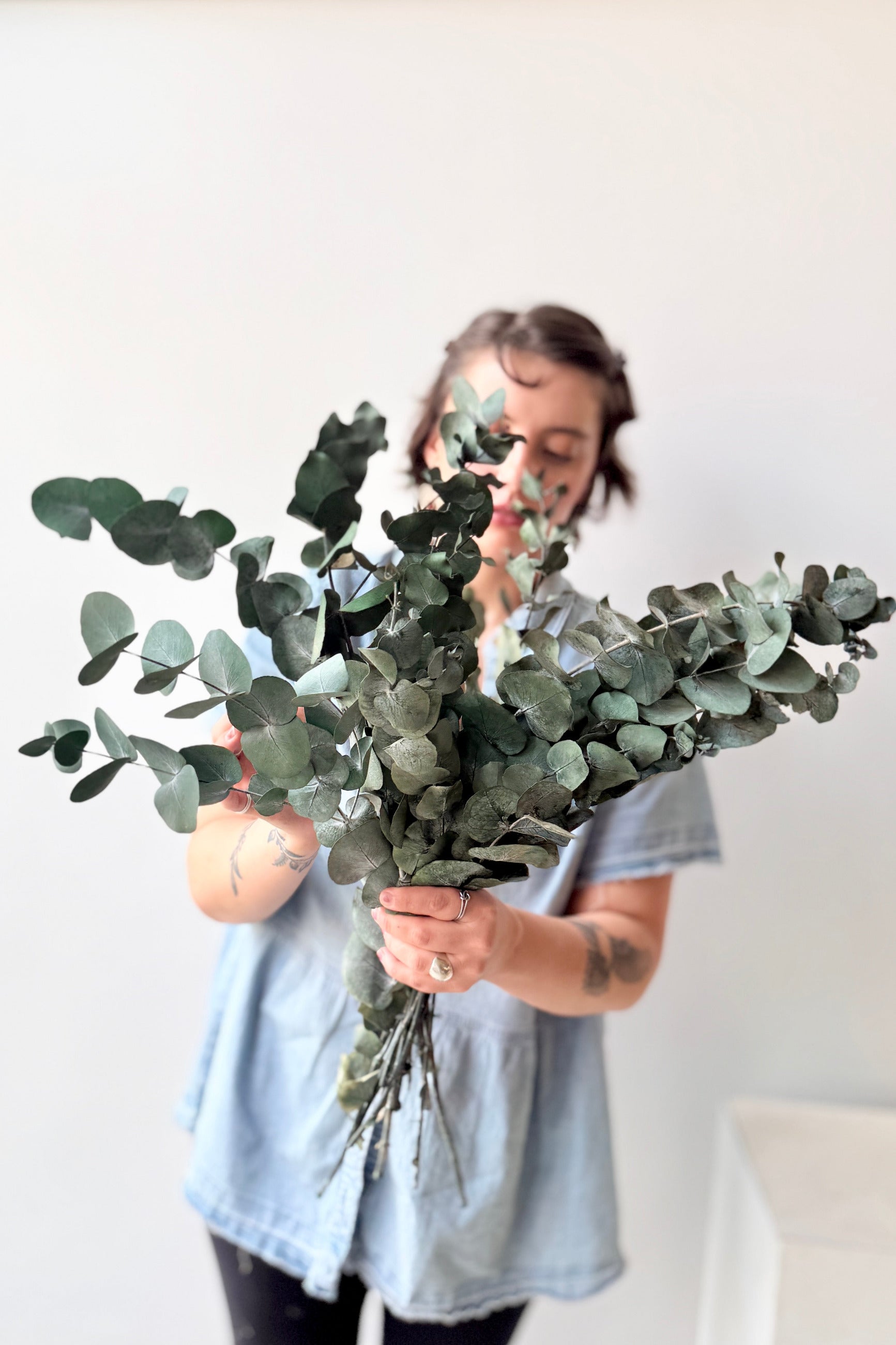 Eucalyptus Spiral Blue Color Preserved Bunch being held by a Sprout Home employee against a white backdrop ©Sprout HOme