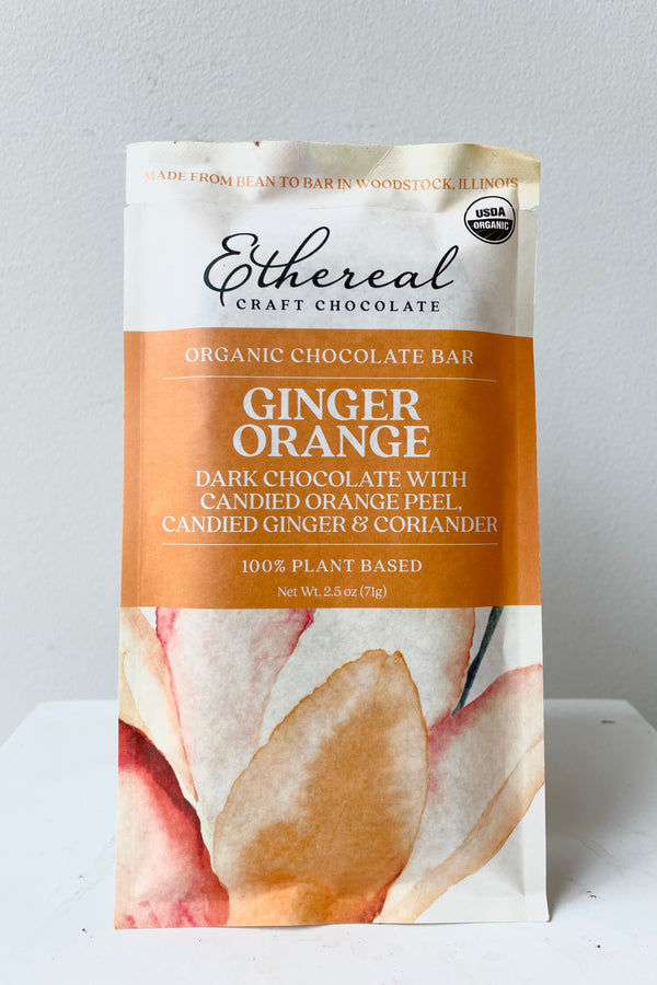 A detailed view of the Ginger Orange Chocolate Bar in white and orange packaging against a white background
