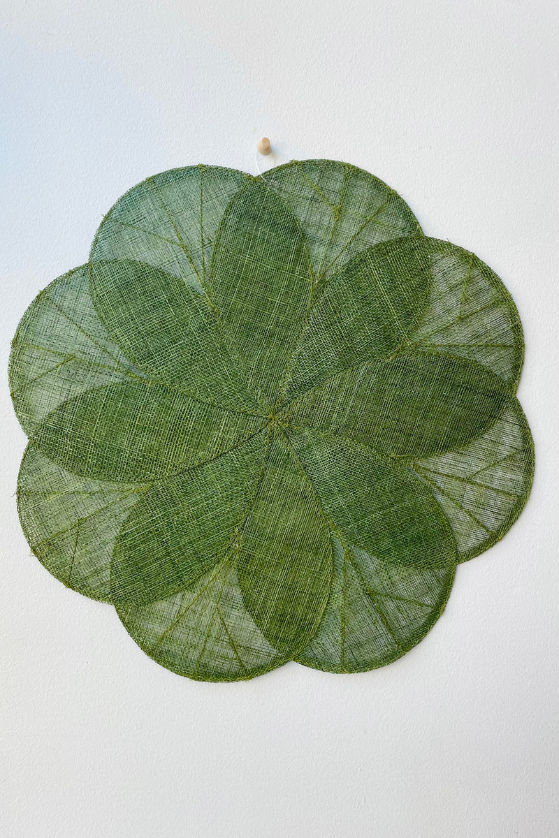 Sheer woven dark green placemat in flower design against white wall