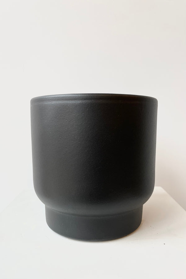 Black ceramic urn shaped cachepot small against white background