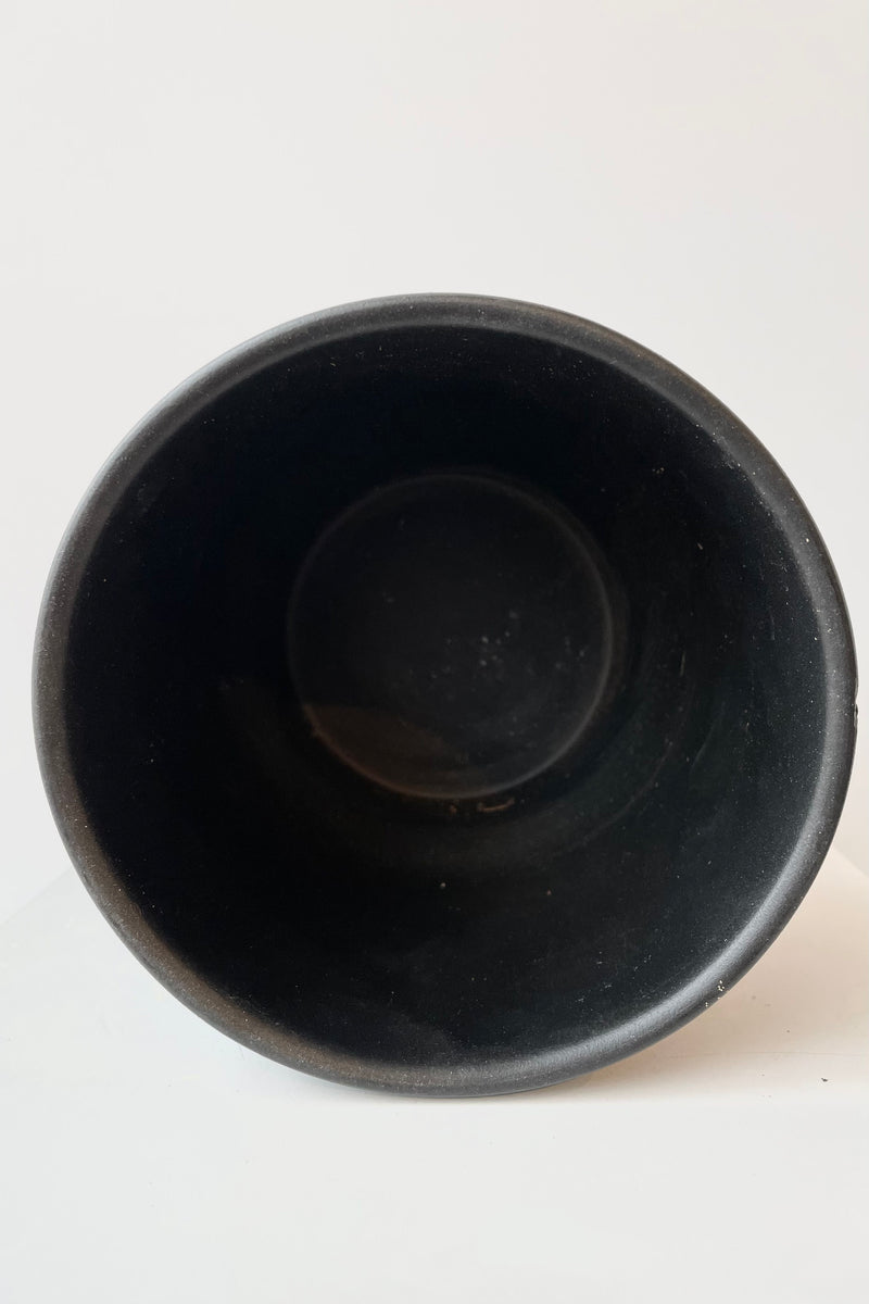 Interior of black ceramic cachepot no drain hole against white background