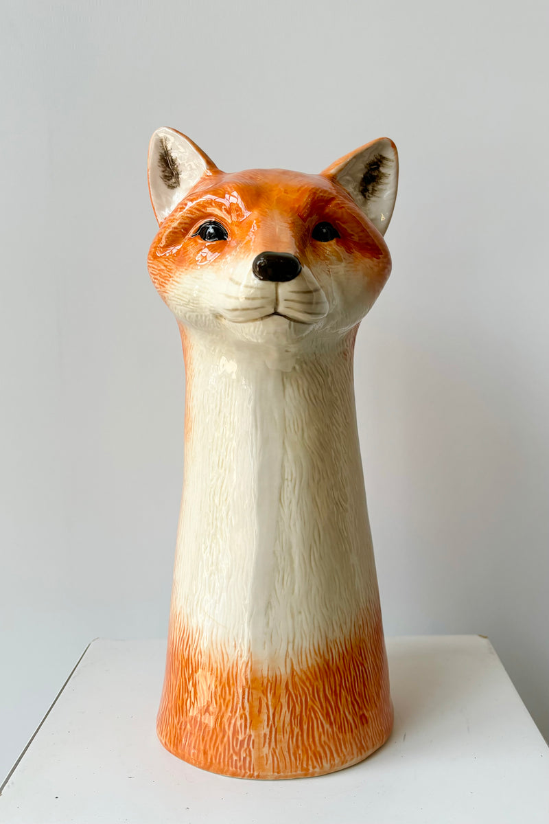 Ceramic vase in the shape of an orange and white fox head against white background.