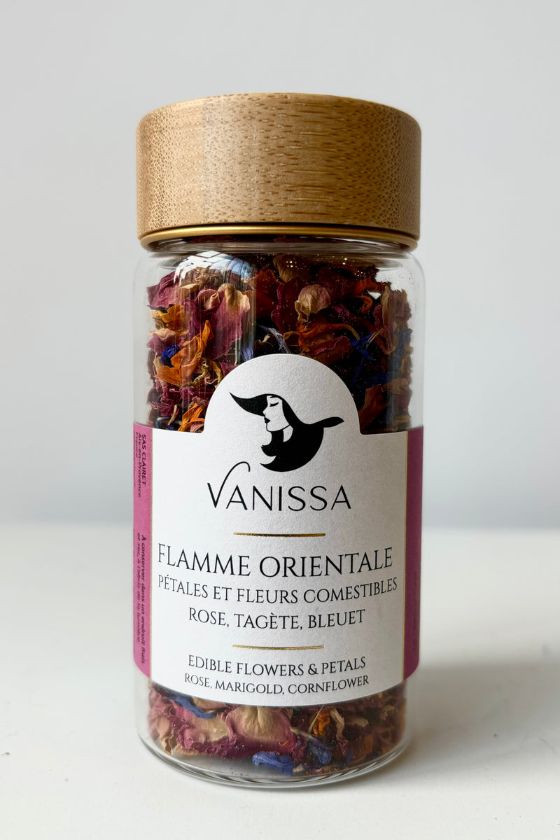 Front view of glass jar with dried flower petals composed of rose, marigold and cornflower petals against white background