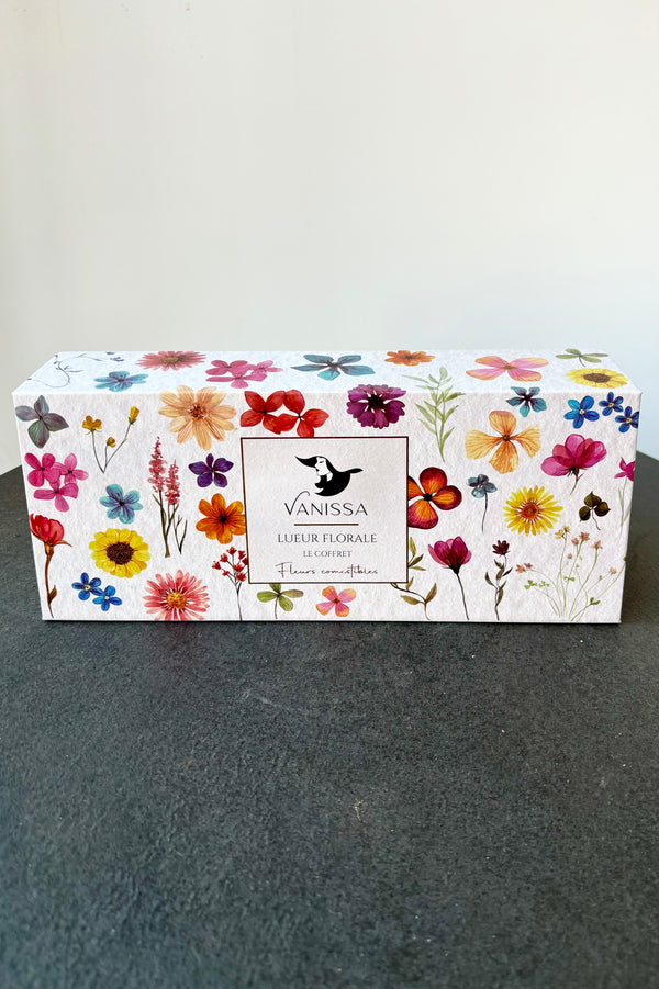 Closed rectangular gift box set with images of variously colored flowers throughout against white background