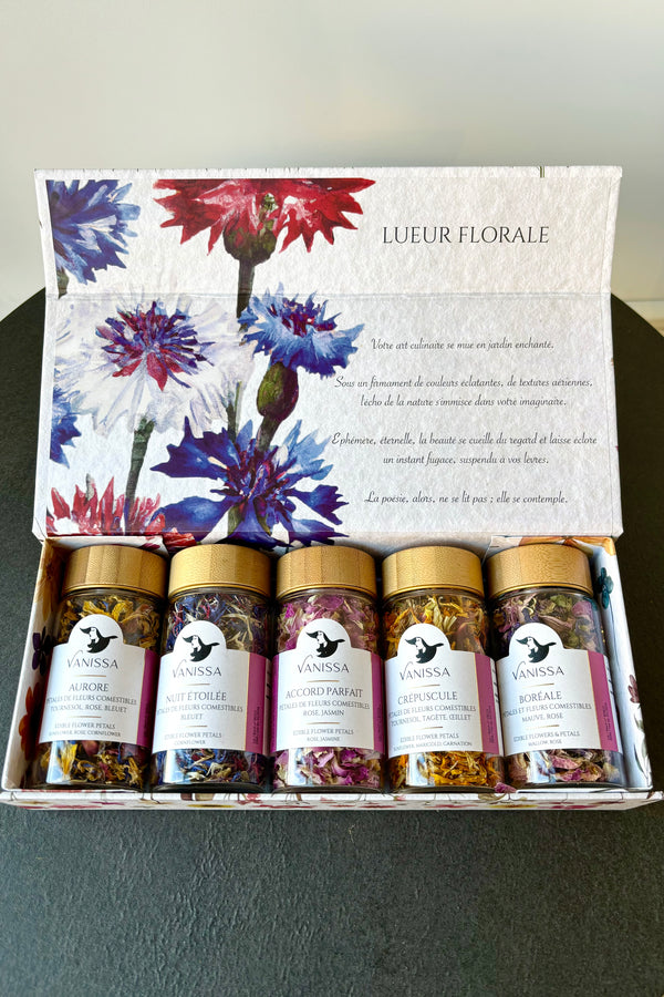 Box set of five edible flower mixes in clear glass jars arranged in a rectangular box displayed in an open position with an image of dianthus flowers 