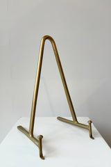 Brass display stand featuring two horizontal prongs connected by a vertical arch for support against a white background