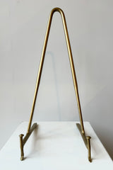 Brass display stand featuring two horizontal prongs connected by a vertical arch for support against a white background