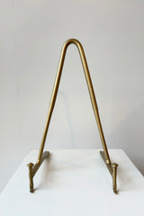 Brass display stand featuring two horizontal prongs connected by a vertical arch for support against a white background