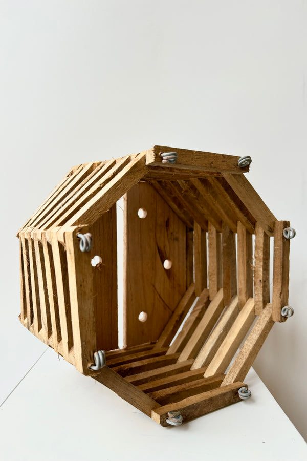 Side view of wooden octangonal slatted basket with metal rings for sting attachment, not included, against white background 