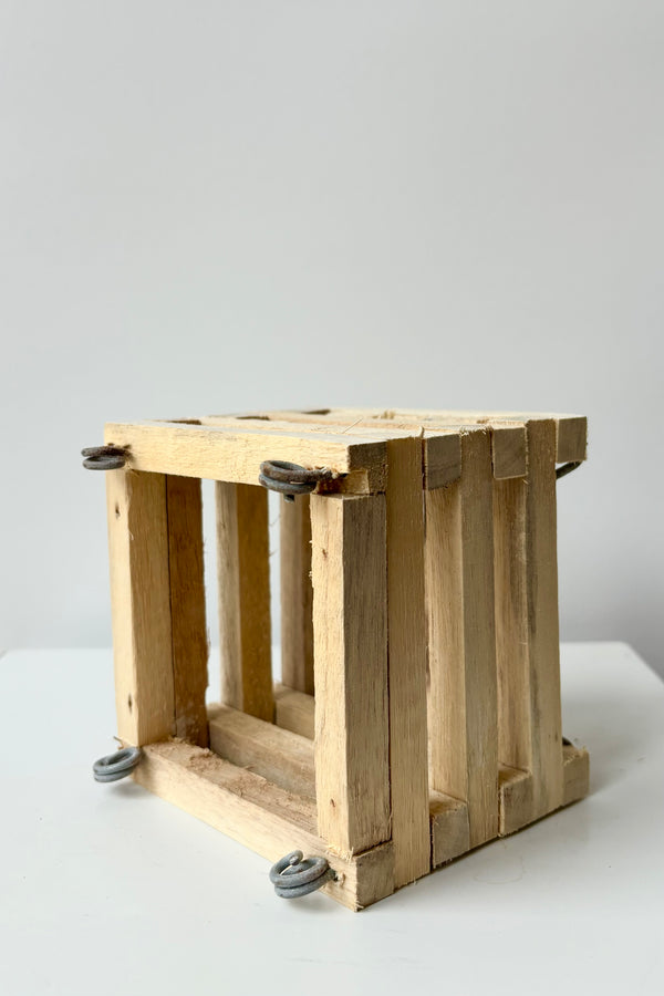 Side view of a wooden slatted vanda basket with metal rings for string attachment, not included, against white background