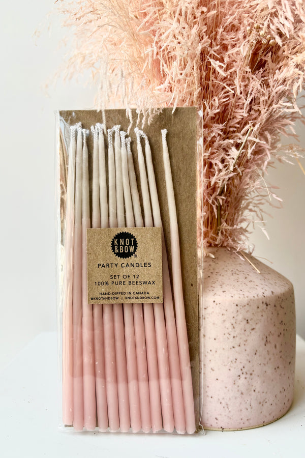 Set of twelve, tall ombre pink candes against white background