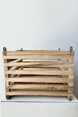 Side view of a wooden slatted vanda basket with metal rings for string attachment, not included, against white background