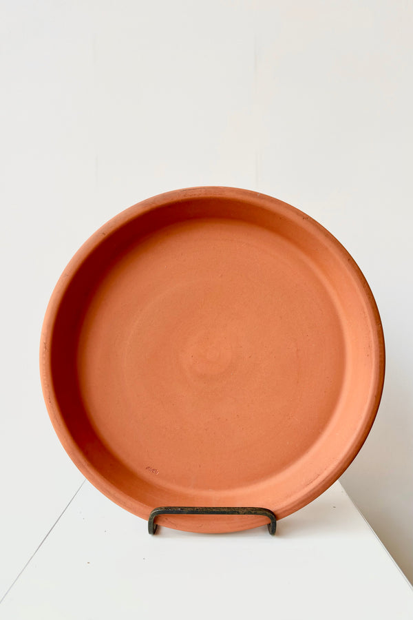 Red twelve inch terra cotta saucer in display stand against white background