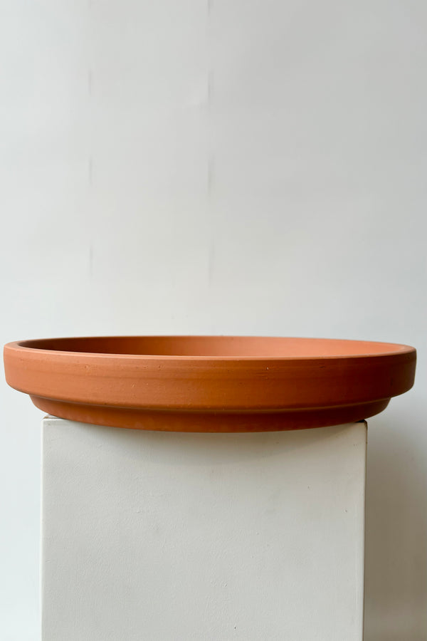 Side view of red terra cotta clay saucer to fit a fourteen inch pot