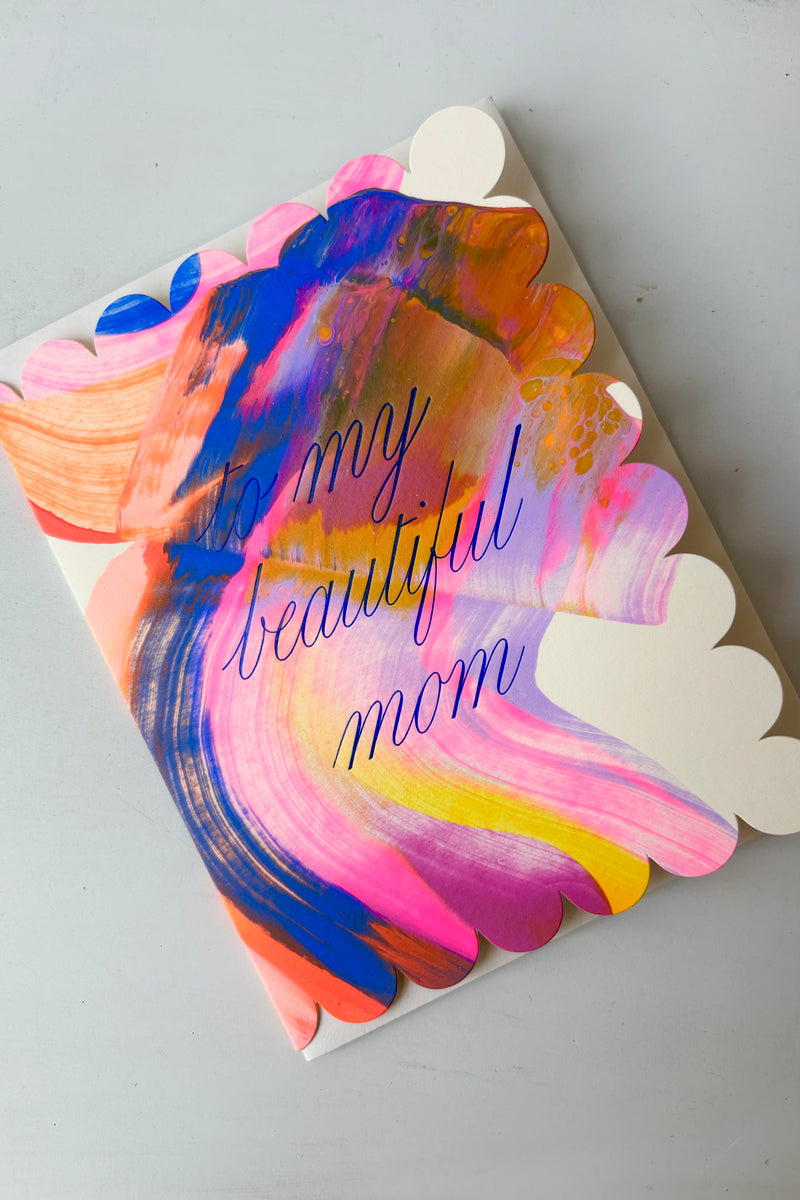 Hand painted greeting card with scalloped edge decorated in multicolored streaks and blue lettering that says to my beautiful mom