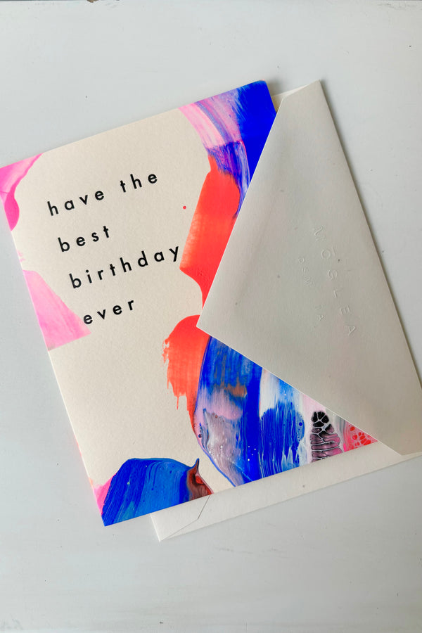 Hand painted greeting card with abstract design in pink, blue, and red with black letting that says have the best birthday ever displayed with white envelope