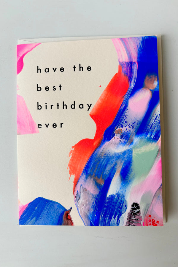 Hand painted greeting card with abstract design in pink, blue, and red with black letting that says have the best birthday ever against white background