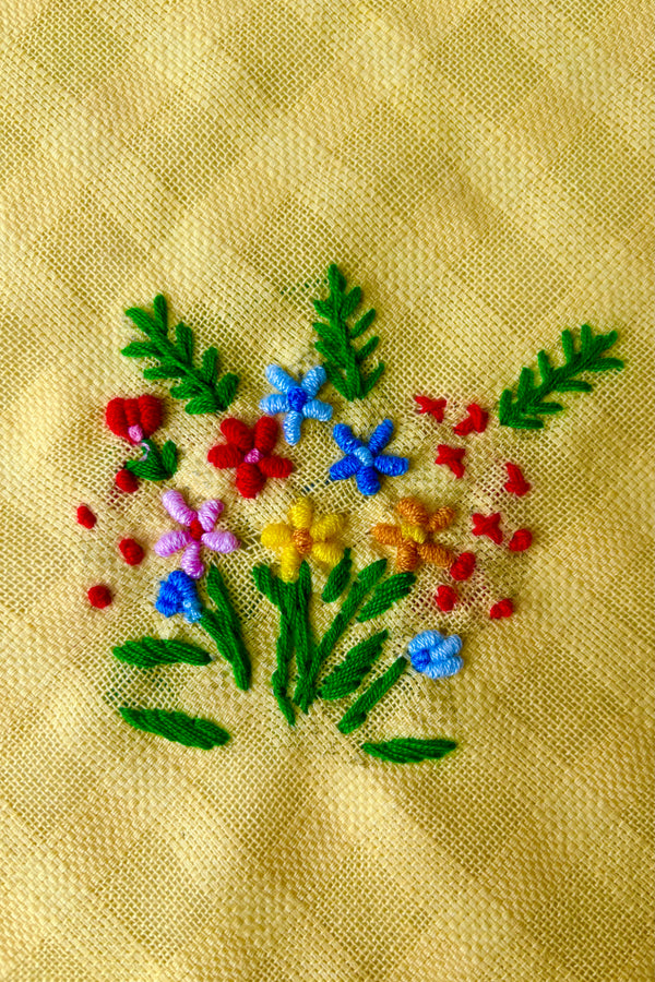 Close up of embriodered floral motif on yellow handmade tea towel
