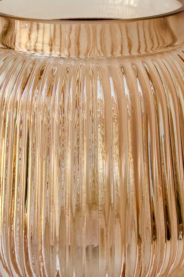 Close up of rose tinted glass vase with vertical ribbing
