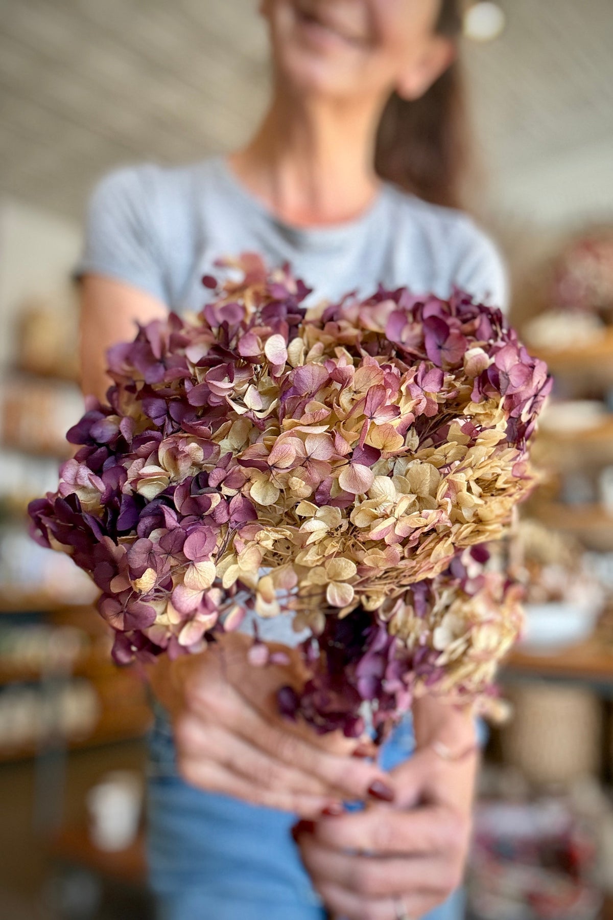 Hydrangea Cabeza Natural Lilac Color Preserved Stem been held I hand with a blurred background ©Sprout Home