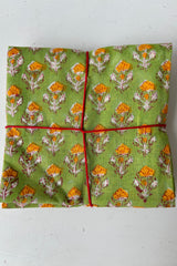 Set of four handsewn napkins featuring orange flowers on a green background on a white table