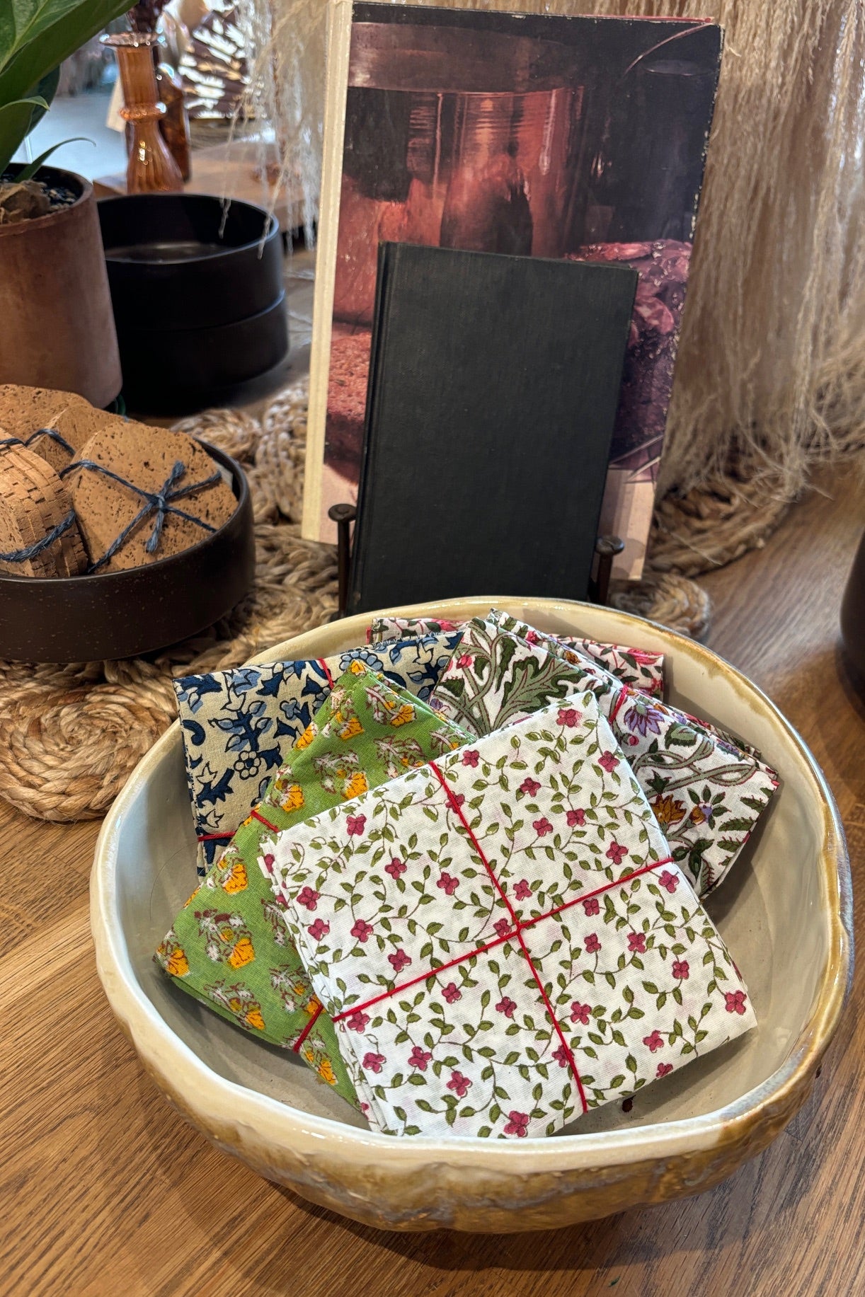 Assorted sets of hand sewn fabric napkins displayed in a ceramic bowl on a wooden table