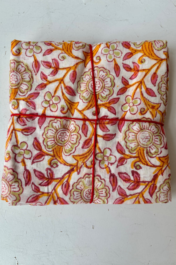 Set of four hand sewn napkin with orange and pink floral filagree pattern throughout against white background