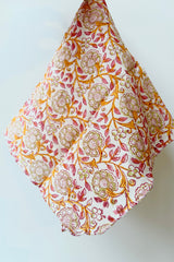 Hand sewn napkin with orange and pink floral filagree pattern throughout against white background