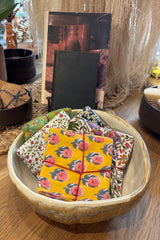 Assorted sets of hand sewn fabric napkins displayed in a ceramic bowl on a wooden table