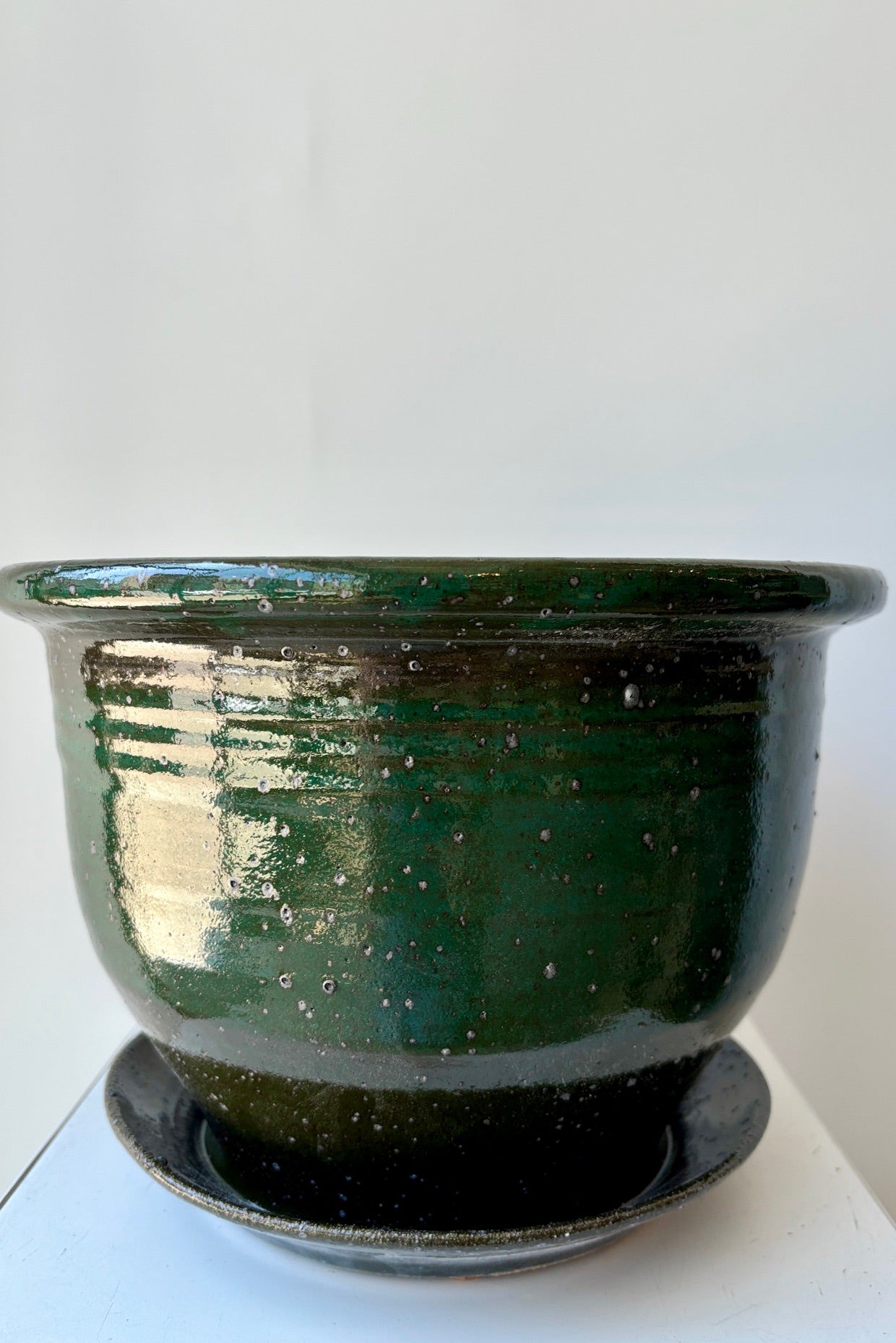 Eight inch clay planter with drainage hole and attached tray in a jade green glaze flecked with silver specks against a white background