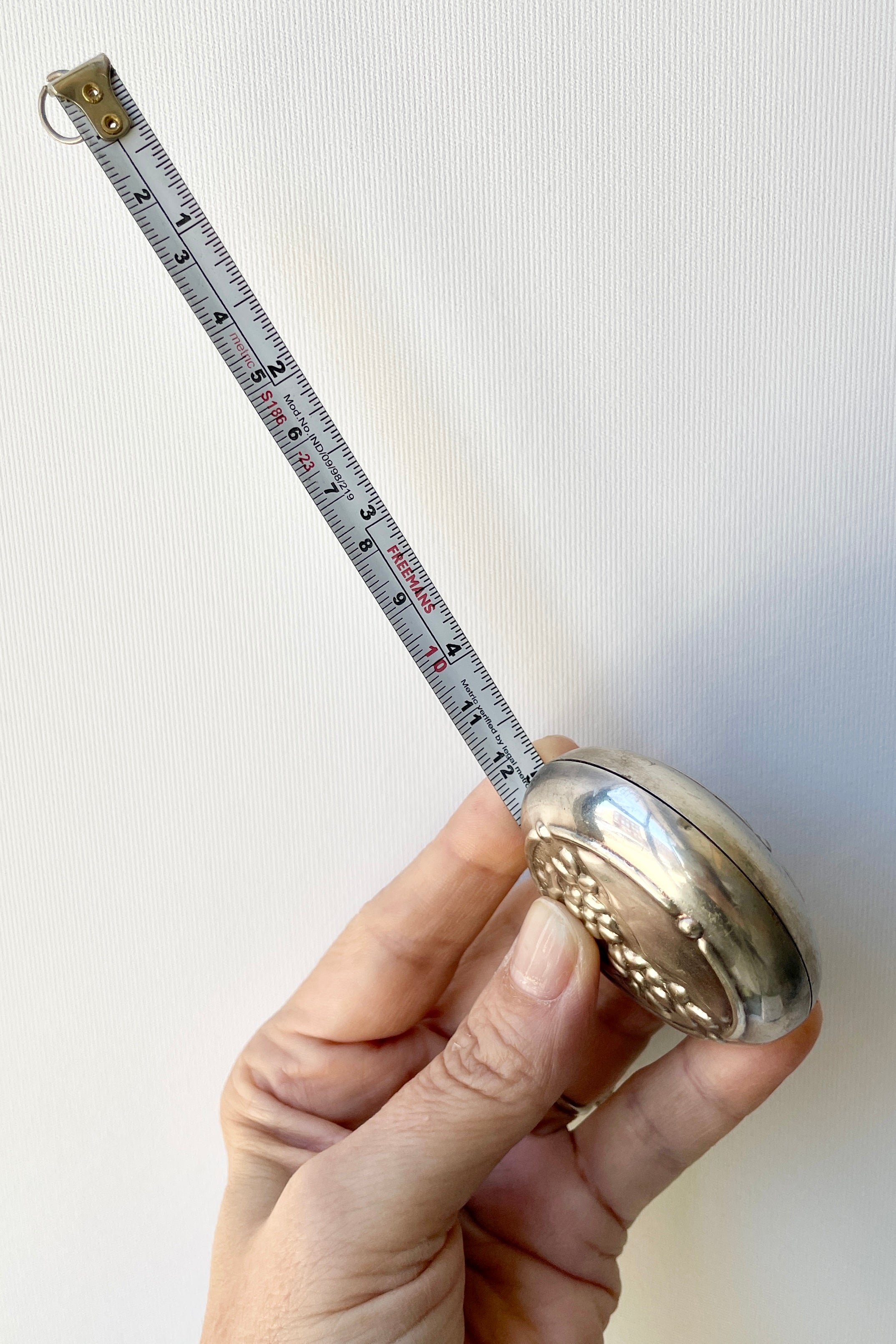 Flowers measuring tape from the side with the tape drawn being held in hand.