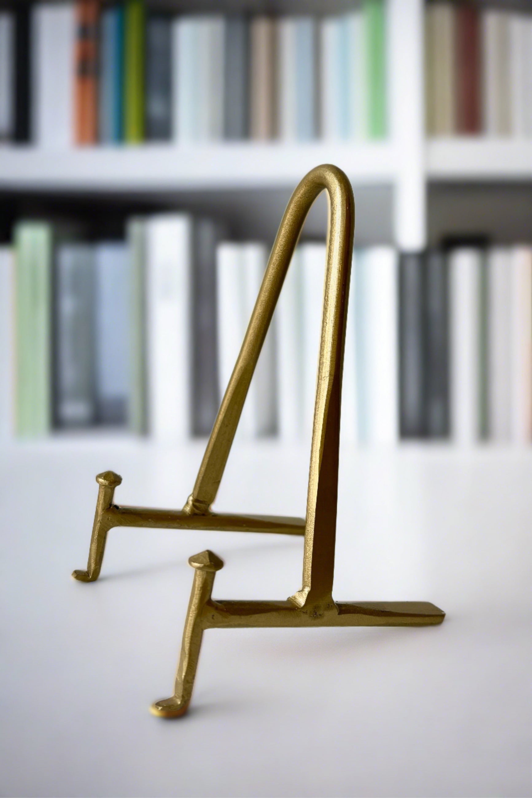 Small Antique Brass Display stand in front of a monochromatic library wall. ©Sprout Home
