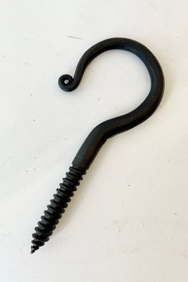 A threaded blacksmiths hook at Sprout Home against a white wall. 