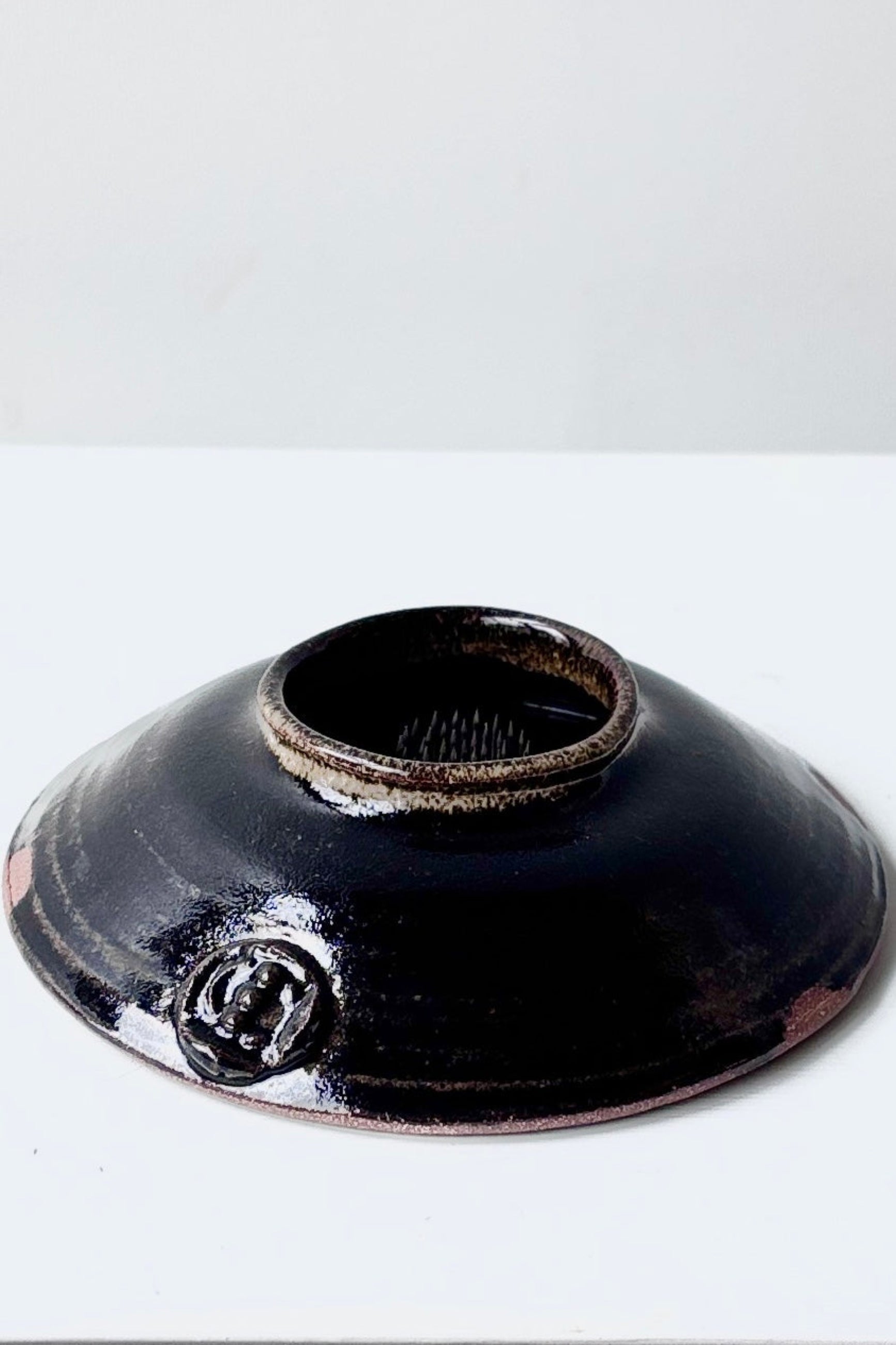 Side view of glazed black ceramic Ikebana vase against a white background ©Sprout Home