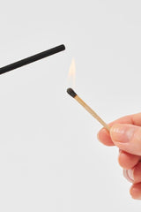 Lighting an Elements incense stick with a match detail.