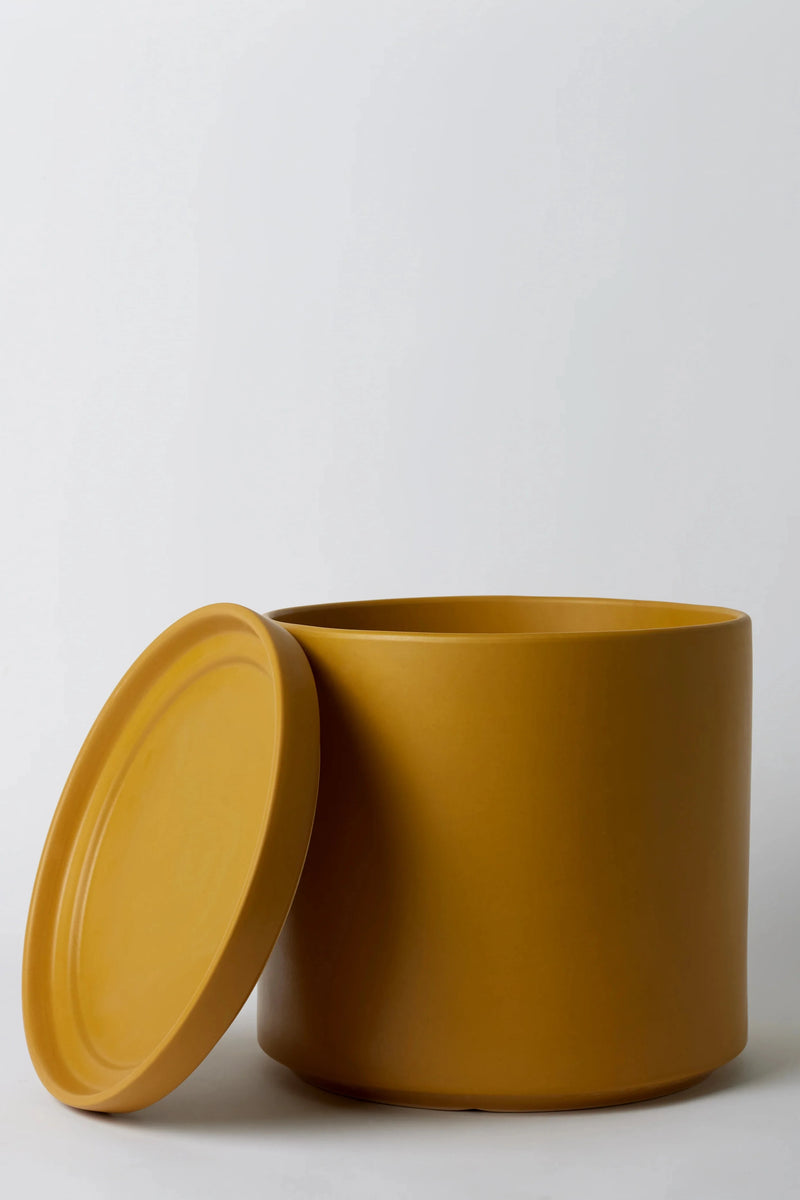 LBE Design Solid Goods Mustard Cyliner and saucer with its saucer leaning up against the empty planter