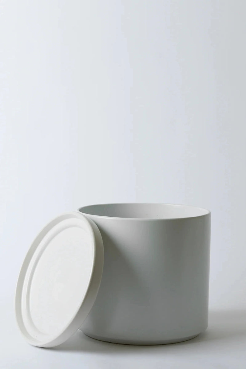 LBE Design Solid Goods planter and saucer in white with its saucer leaning against the pot.