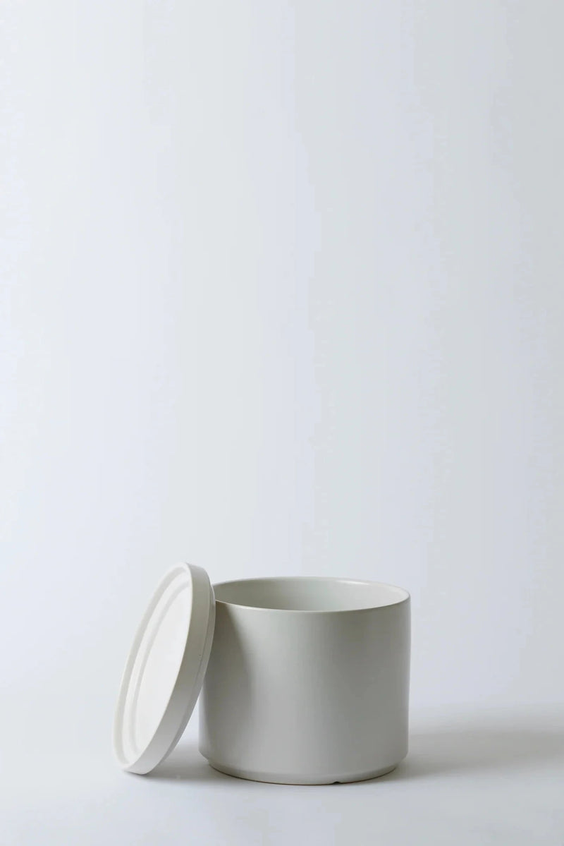 LBE Design white Solid Goods cylinder and saucer with the saucer leaning on the pot.