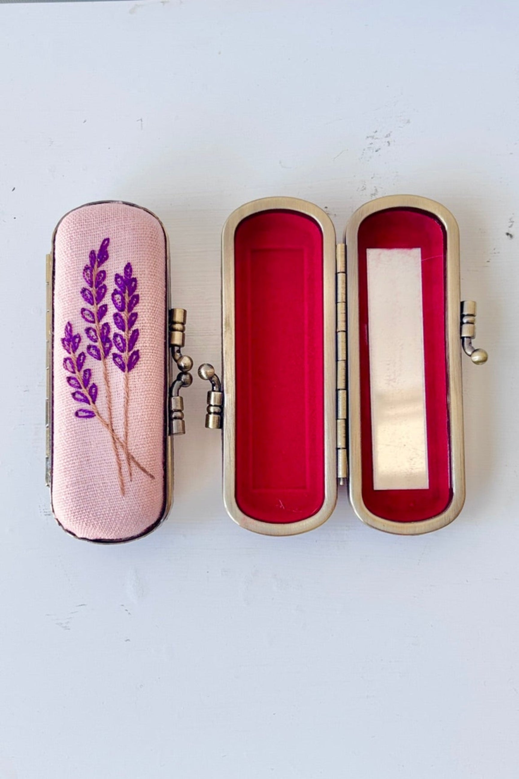 Decorative case with floral embroidery on a lavender background with red velvet and  mirror inside ©Sprout Home