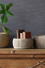 A set of faux rattan shallow planters with the small one holding books on top of a dresser.