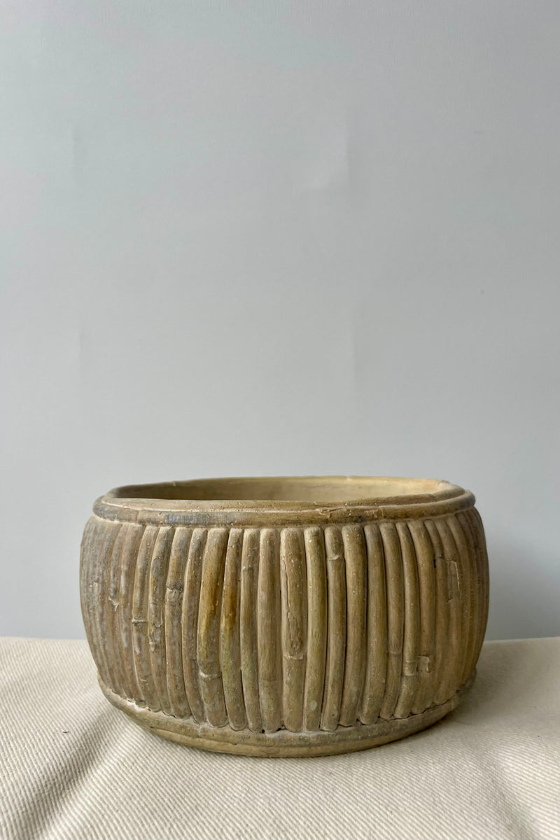 Medium shallow concrete faux rattan planter empty against a white background on a white tablecloth.