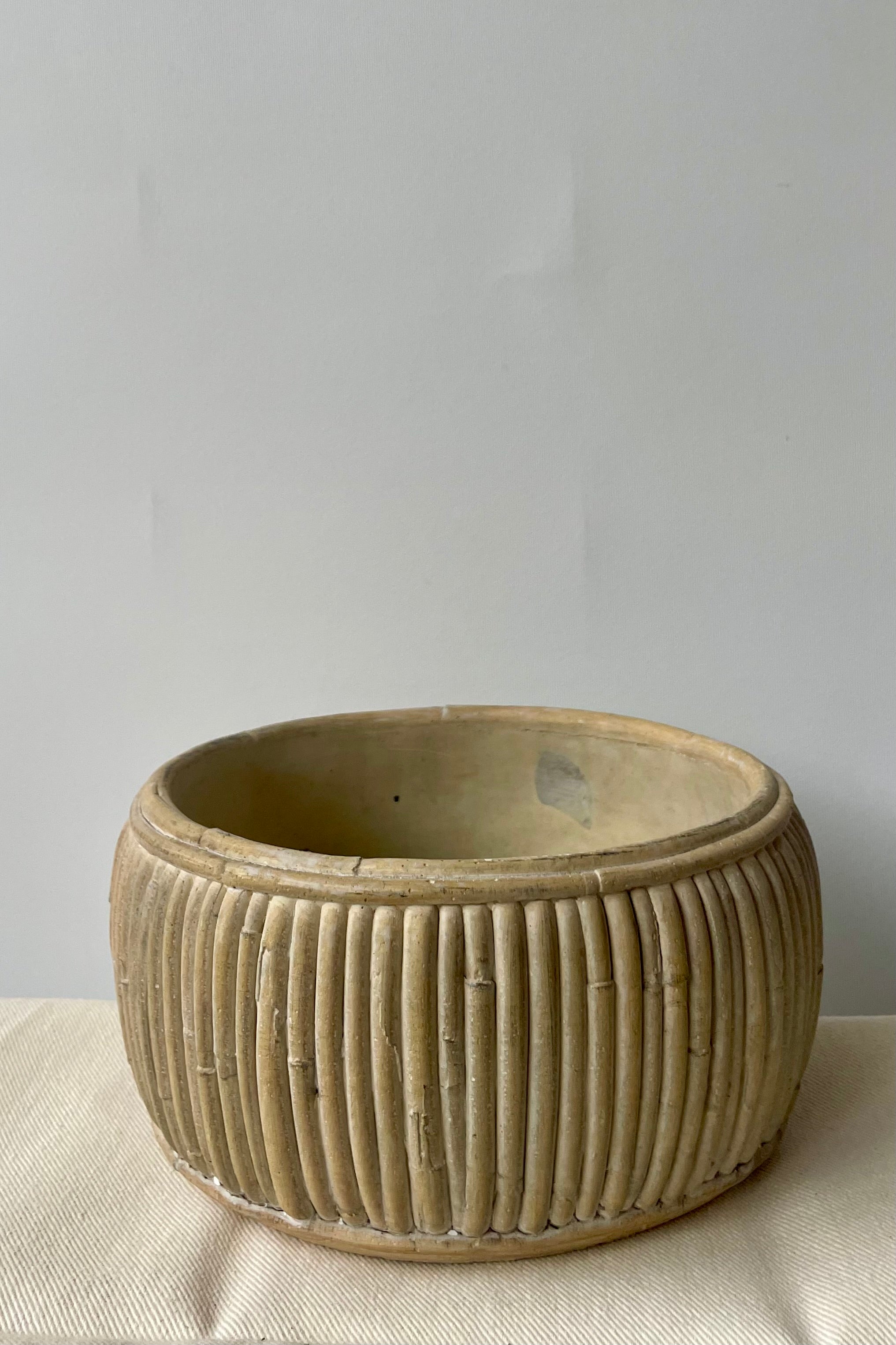 Small shallow concrete faux rattan planter empty against a white background on a white tablecloth.