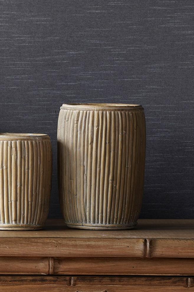 Medium tall faux rattan concrete planters in the center with a smaller one to the side against a gray wall and on top of a wooden dresser