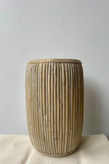 Large tall concrete faux rattan planter against a white background on a white tablecloth.