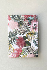 The floral and foliage front of the Botanical Card against a white wall. 