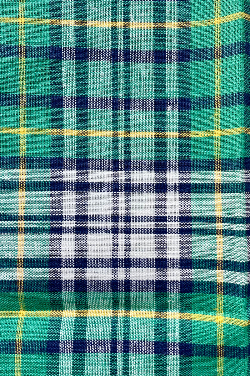 Photo from above. A Helen Green linen kitchen towel shown from above. The Plaid is mostly green with dark blue white and yellow.