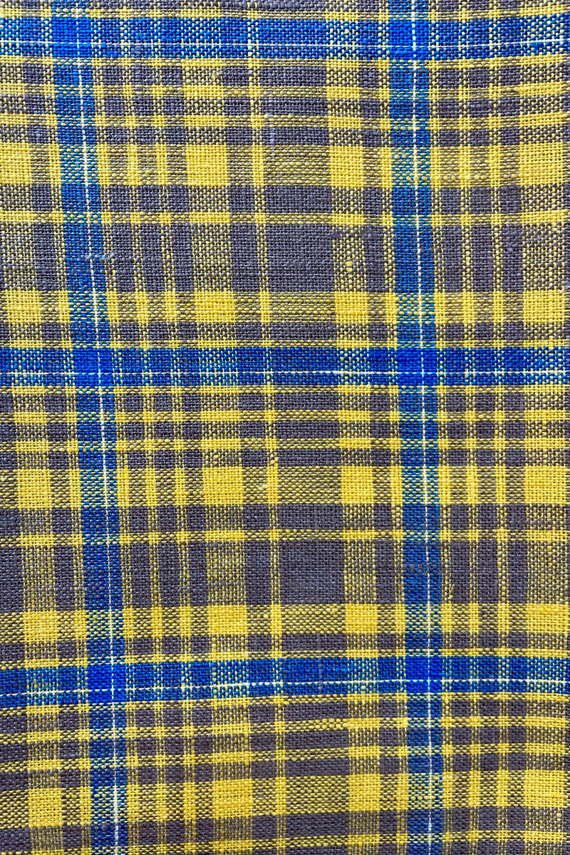 Close photo of a amber yellow plaid linen kitchen towel. The plaid is mostly yellow with taupe and light blue.