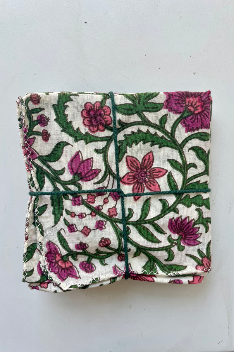 Set of four folded Amaryllis pattern napkins on a white surface.