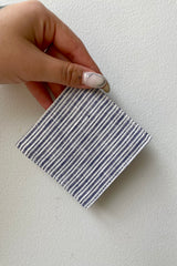 The Erin Linen coaster being held against a white wall. 