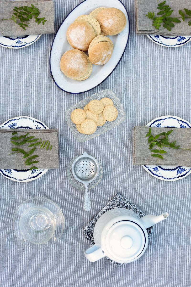 Grey with White stripe linen tablecloth by Fog Linen Work with a table setting in a lifestyle shot shown from above.